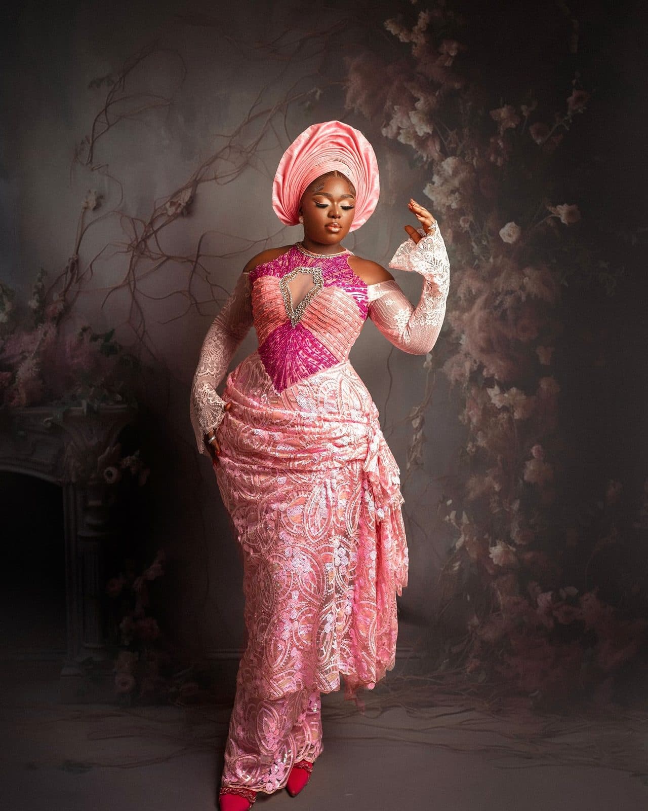 A wedding guest in pink lace with a matching gele