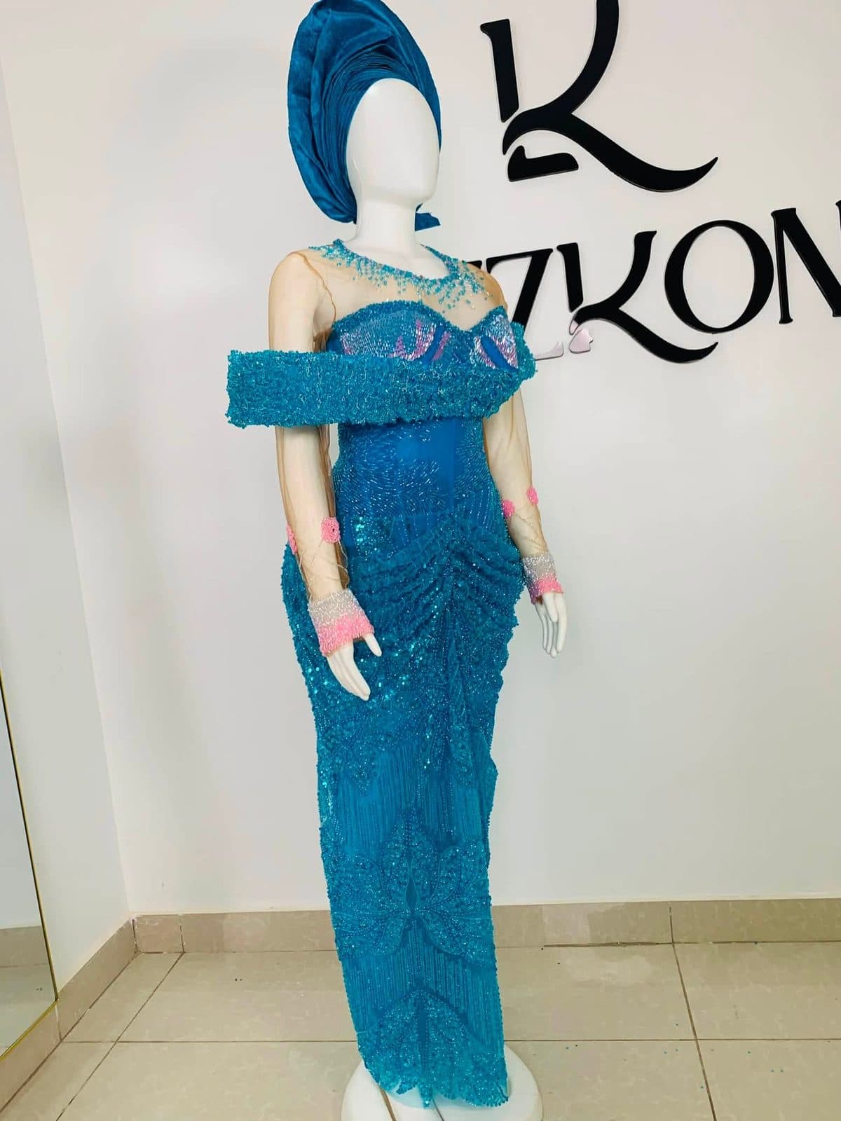 A teal gown on a dress form in front of the Lizkon wall in Abuja
