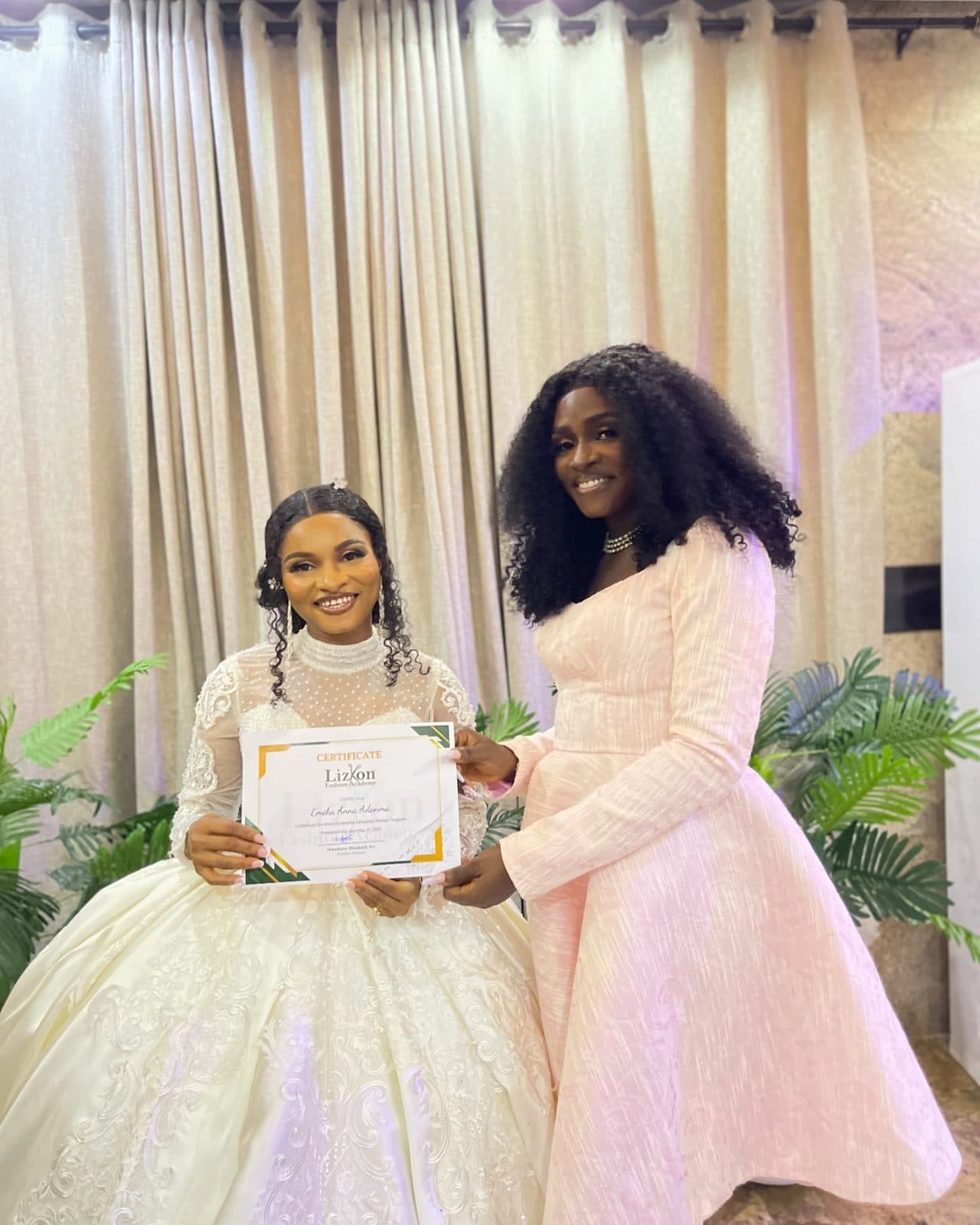 A graduate with her certificate in a white ball gown
