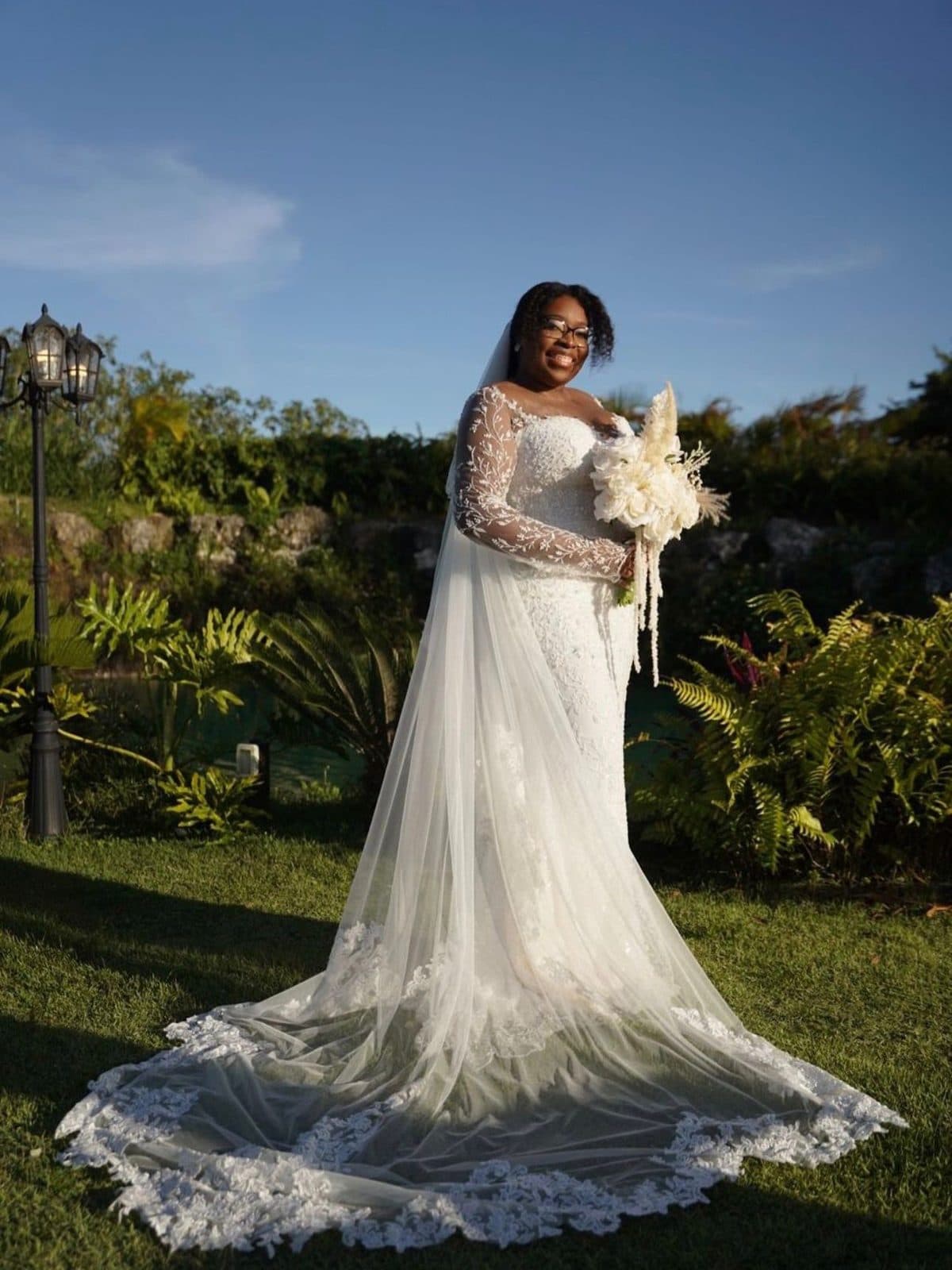 The bride in her lace mermaid gown and veil in a garden