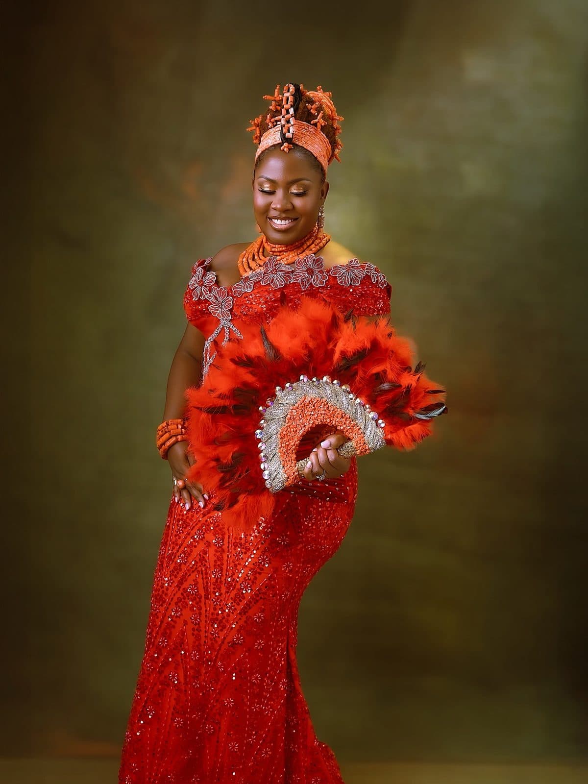 The bride seated in her red beaded lace and coral beads