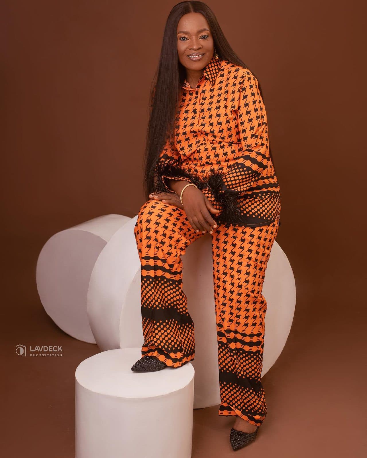 An older woman in an orange Ankara two-piece