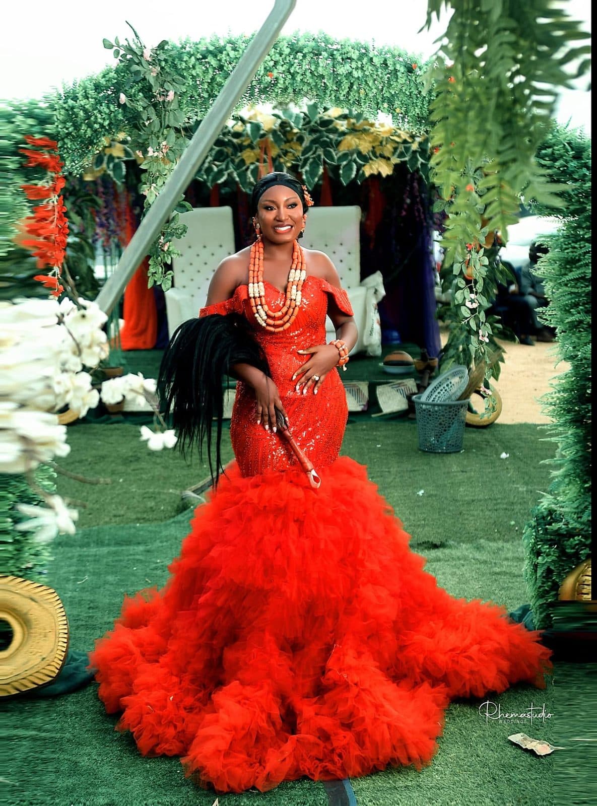 A bride in a red tulle mermaid gown in a garden
