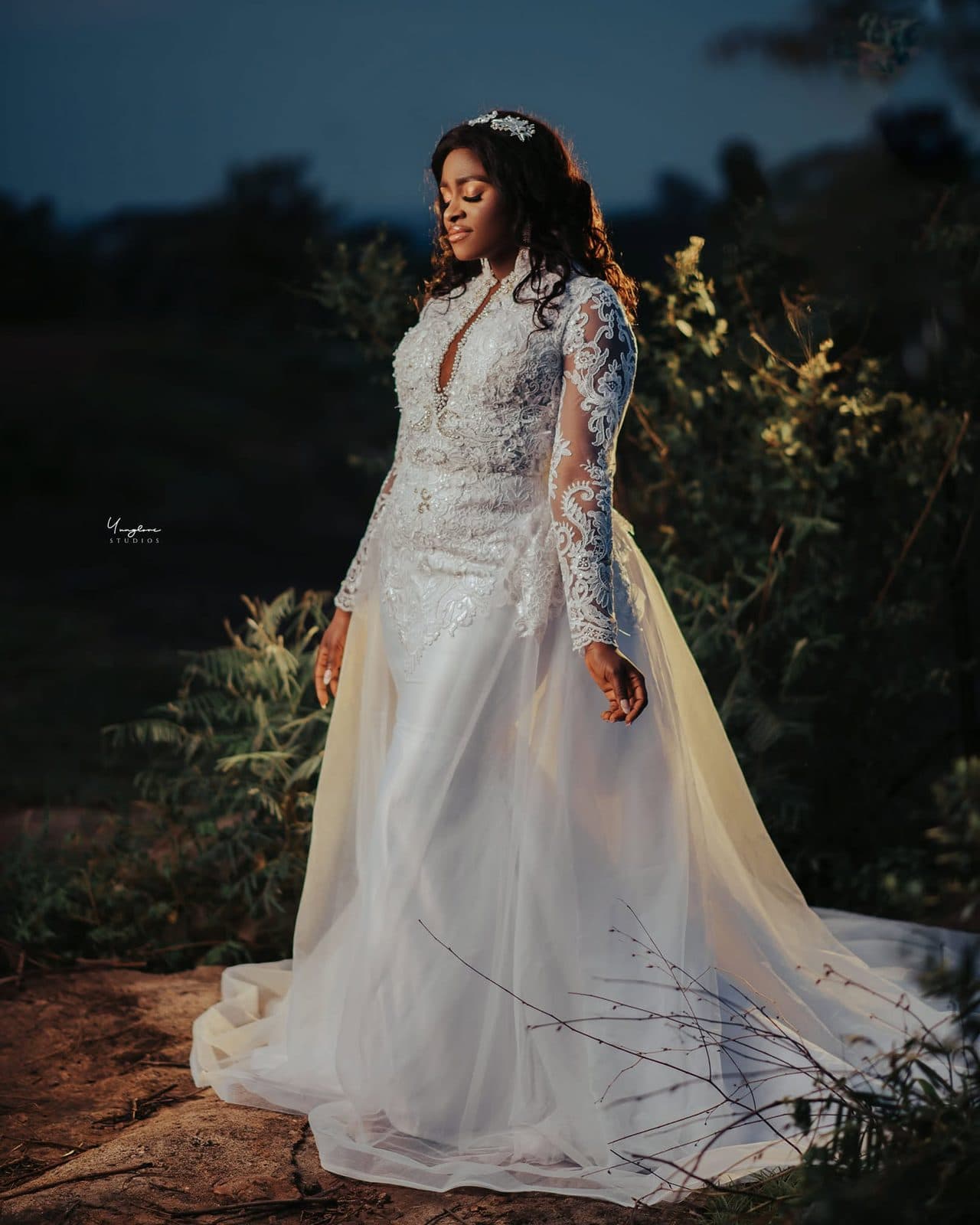 A bride outdoors in a lace gown with a long veil