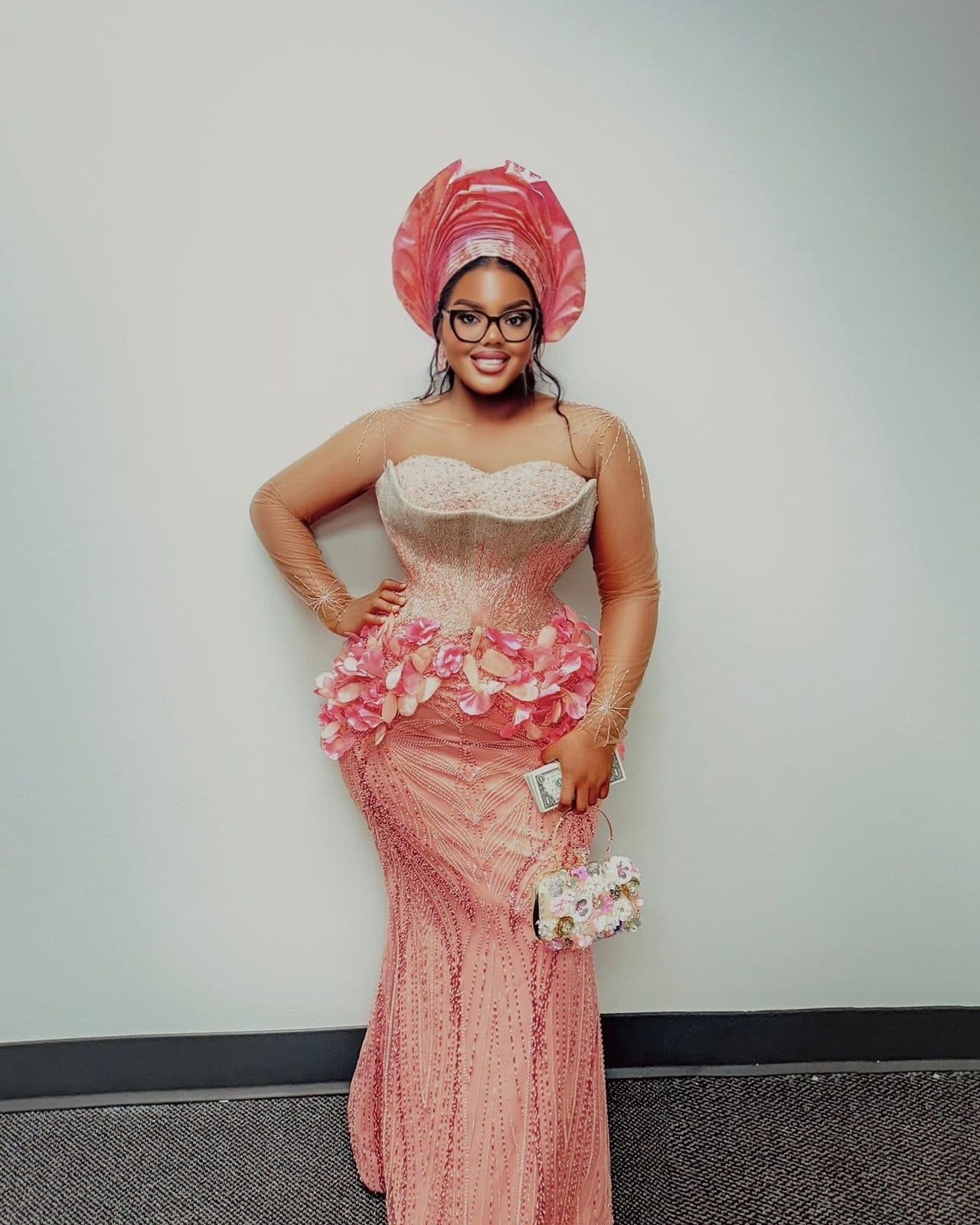 A guest in a peach corset gown with a gele
