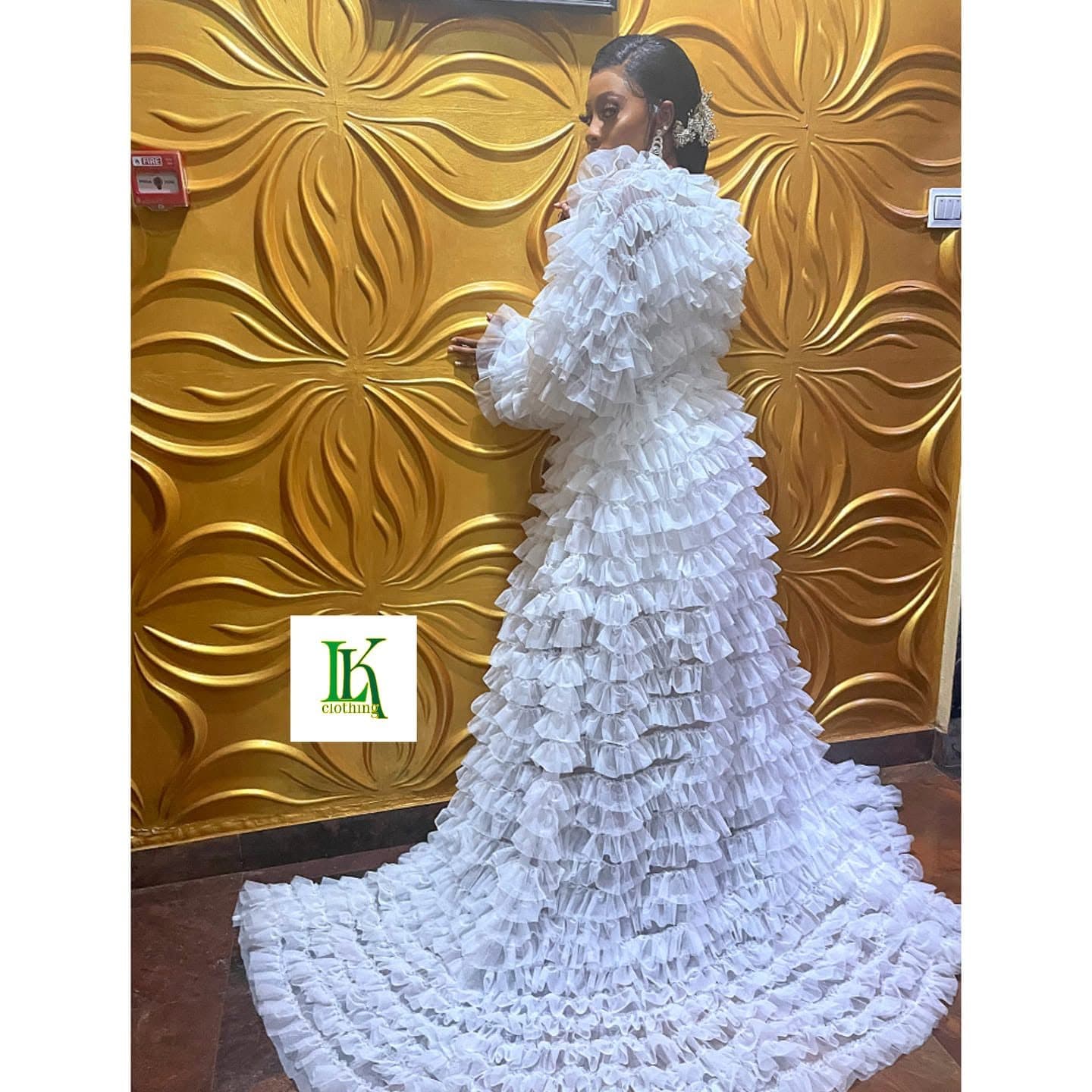 The back of a white gown covered in tiers of fabric flowers