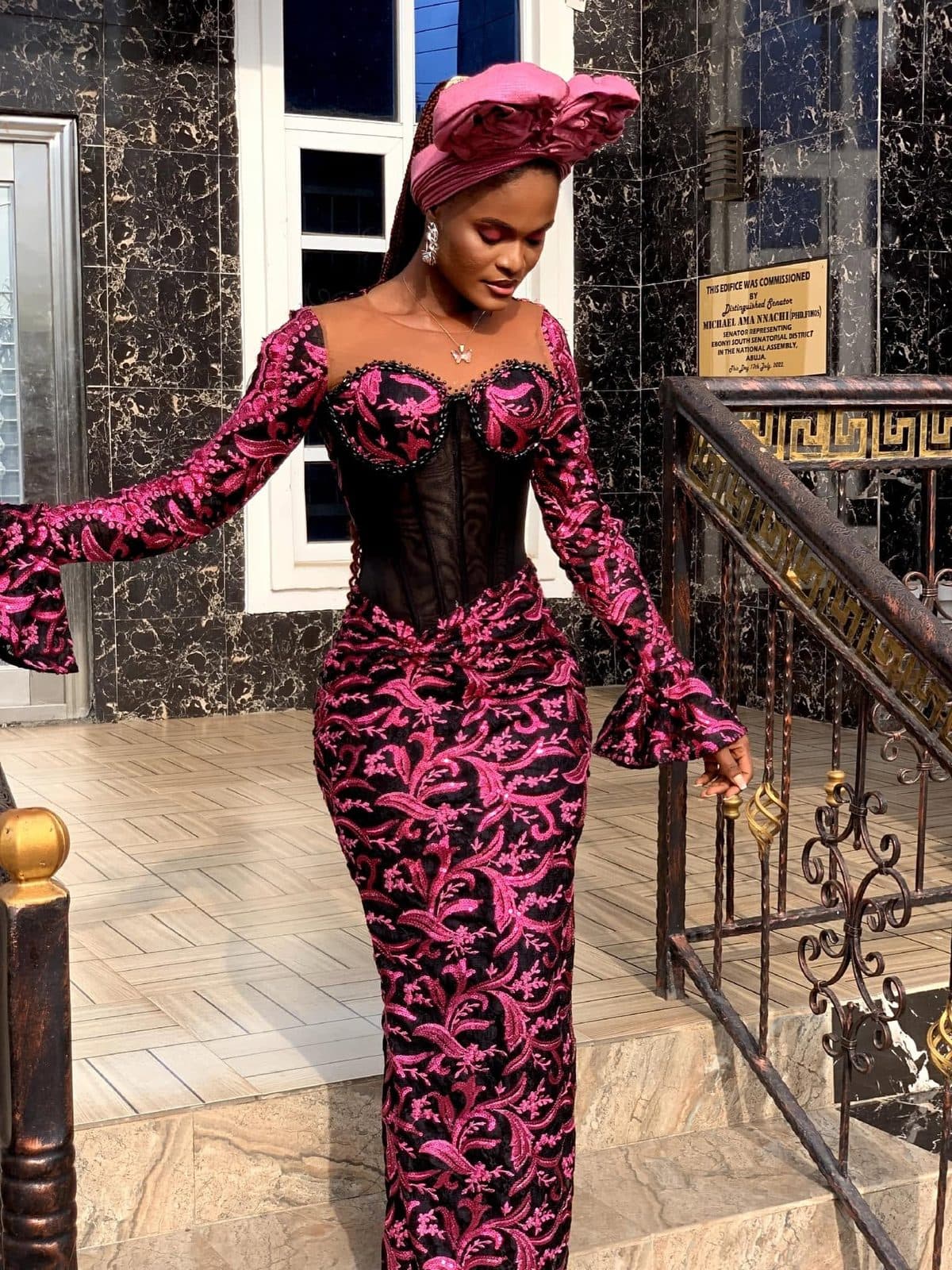 A wedding guest in a black corset and pink lace on a staircase